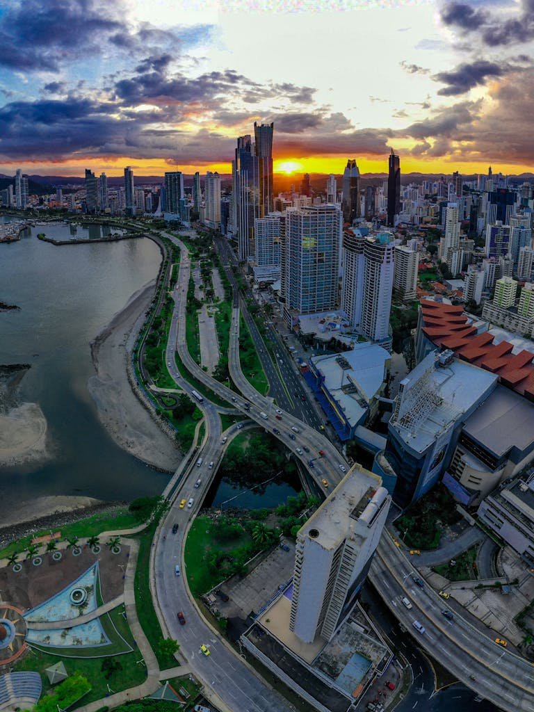 Drone shot of Panama City's skyline and coastline during sunset, showcasing skyscrapers and vibrant city life.