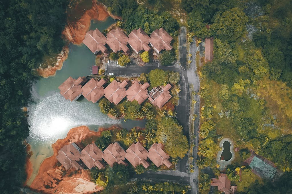 Scenic aerial view of houses and road on river coast with sand shore and forest